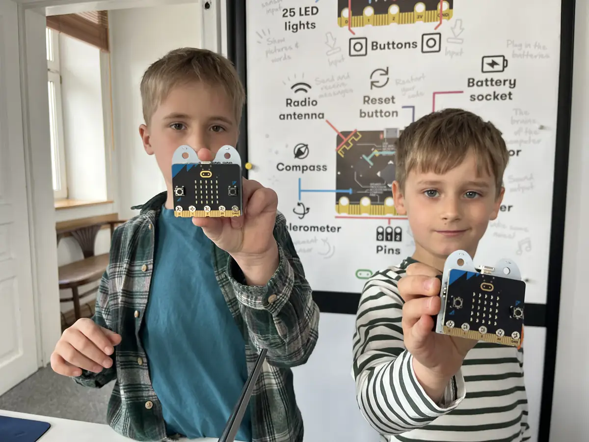 Dzieci pokazują własne projekty z micro:bit na warsztatach JuniorAI