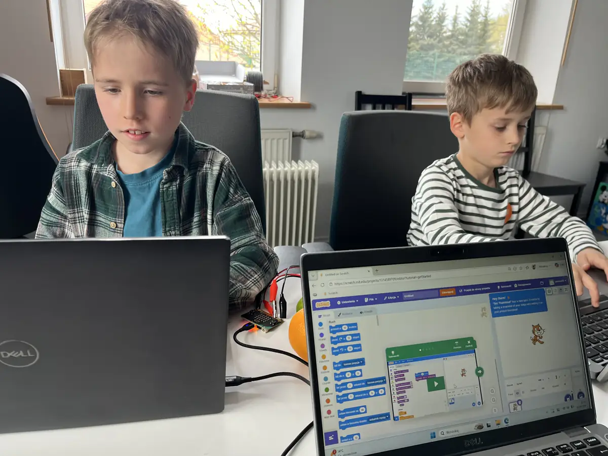 Dzieci programują przy laptopach na zajęciach JuniorAI