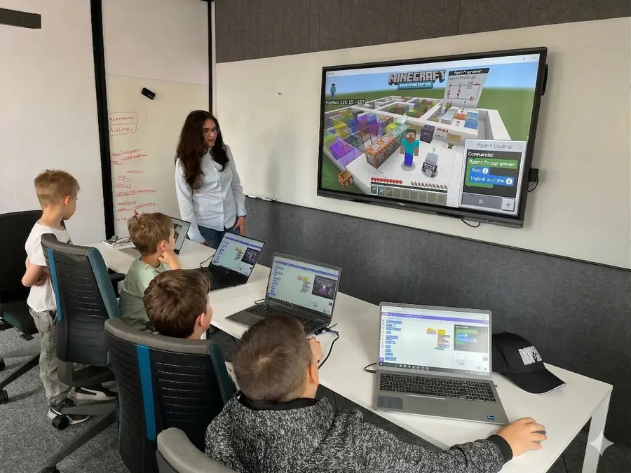 Zajęcia z Minecraft Education — instruktorka i dzieci przy laptopach